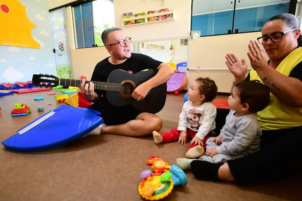 Professor tocando violão para os bebês no berçário do Colégio Basic